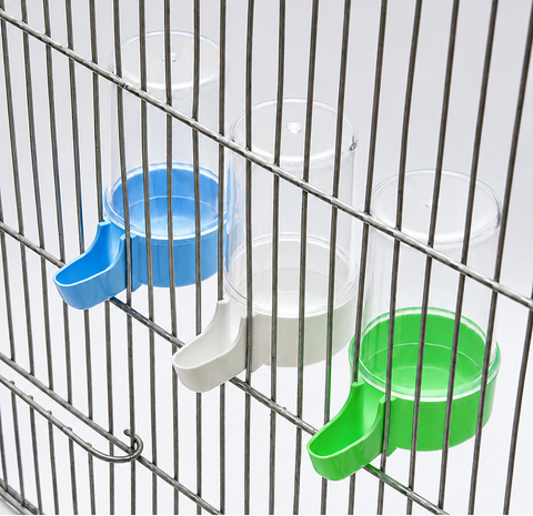 Three clear plastic pet water bottles with blue, white, and green dispensers mounted on a metal wire cage. The Petsmart logo is visible in the top left corner, and a red contact banner is at the bottom.